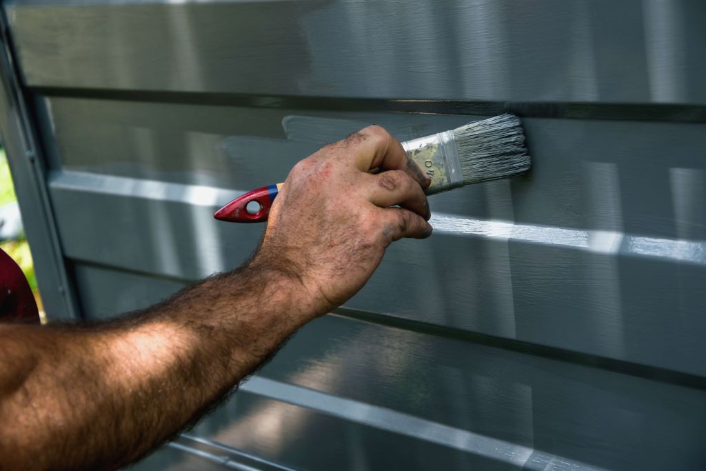 How to Choose Paint for Aluminum Garage Door? When it comes to painting your aluminum garage door, the process can be quite overwhelming. There are a multitude of factors to take into consideration, such as the sheen levels, durability, and of course, the right color. With so many options available, it's understandable to feel like you're in over your head. However, with the right information and guidance, you can select the ideal paint that will not only make your garage door look great but also ensure that it remains in top condition for years to come. Remember to consider the weather conditions in your area, as well as any specific features or characteristics of your garage door that may affect the painting process. With a little research and careful consideration, you can select the perfect paint that will help enhance the look of your home and provide long-lasting protection for your garage door. Why Painting Aluminum Garage Doors is Important Painting your aluminum garage door serves several important purposes: Protection A fresh coat of paint protects the aluminum from oxidation and corrosion caused by exposure to the elements. Over time, unpainted aluminum can begin to pit, flake, and deteriorate. Paint acts as a barrier to prevent this type of damage. Appearance Paint gives your aluminum garage door a clean, uniform appearance. It covers any scratches, dings, or discoloration over years of use. This keeps your garage door looking new and refreshed. Weather Resistance Exterior paints are formulated to withstand exposure to the sun, rain, snow, and temperature extremes. This weather-resistant paint helps aluminum garage doors maintain good looks despite harsh weather. Increased Home Value An eye-catching garage door with a fresh coat of paint can increase your home's curb appeal. Little enhancements like this can make your house more attractive to potential buyers and increase resale value. Factors to Consider When Selecting Garage Door Paint Choosing the right paint involves evaluating a few key factors: Paint Type You'll need to select an exterior-grade acrylic latex paint. Oil-based paints don't adhere well and will peel quickly. Acrylic latex paints provide excellent adhesion and durability on aluminum garage doors. Sheen Level The sheen refers to how much light the painted surface reflects. For a garage door, opt for a satin or semi-gloss sheen. Gloss is too reflective and flat and is prone to wear faster and dirt pickup. Satin or semi-gloss offers excellent durability. Weather Resistance Look for paints specifically formulated to withstand heat, cold, moisture, and sun exposure. Acrylic latex paints that say "exterior" on the label are ideal for garage doors. Color Pick a color that complements your home. Darker colors add richness, while light colors brighten up the facade. Neutrals like tans, grays, and whites are classic options. Ease of Application Consider how you want to apply the paint. Brush-on formulas offer versatility for more minor touch-ups. Spray paints allow for quick, full coverage. Buy quality brushes, rollers, or sprayers to get the best results. You can zero in on the right paint for your aluminum garage door by evaluating these factors. Preparing and Cleaning the Garage Door Proper prep work is crucial for achieving outstanding results. Here are tips on getting your aluminum garage door ready for paint: Inspect for any cracks, holes, or gaps around panels and seals. Use caulk to fill any problem areas so the paint looks smooth. Wash the garage door thoroughly with a power washer or robust detergent solution. Rinse off any soapy residue. Sand lightly with fine-grained sandpaper. This helps the paint adhere to the slick aluminum surface. Wipe down with a tack cloth to remove any dust or debris. The surface needs to be completely clean and dry before painting. Cover nearby surfaces like windows, walls, and landscaping to protect from splatter. Lay drop cloths below the garage door. For previously painted doors, remove any peeling or cracking paint. Sand, clean, and spot-prime these areas before applying new paint. Proper prep removes contaminants and creates an optimal surface profile for the paint to stick to. Choosing Paint Finish Types You must determine whether a brush-on or spray paint works best for your project. Here's an overview of the painting methods: Brushing Paint Pros: Brush painting allows you to coat the panels, trim, and hardware efficiently. Suitable for more minor touch-ups or covering repairs. Brushes can reach areas that sprayers may miss. Cons: Brushing takes more time and labor than spraying. It can leave visible brush strokes in the finish. Achieving an even coat is difficult. Best For: Smaller DIY paint jobs, older or damaged doors needing repairs, and touch-ups down the road. Quality angled trim brushes are a must. Roller Paint Pros: Using a roller and pan is faster than brushing. Roller covers provide even coverage with a uniform, consistent finish. Cons: Not great for painting detailed areas and hardware. It still requires some brushwork. Prone to drips if applied too thickly. Best For: Full garage door paint jobs. Use high-quality mini foam rollers and a painter's pad for the edges. Spraying Paint Pros: Spraying is the fastest method of application. It provides a smooth, factory-like finish free of brush marks. Great for covering large uniform surfaces. Cons: Overspray can happen, so masking and drop cloths are necessary. Requires more skill to operate the sprayer properly. Best For: Overall painting of all garage door surfaces. Airless sprayers offer the best results for DIYers. Consider how much of the door needs painting and your skill level to choose the ideal application method. Step-by-Step Painting Instructions Follow these steps to apply your selected aluminum garage door paint properly: 1. Prepare the area Cover nearby surfaces and lay drop cloths. Remove hardware if possible. Fill any holes and sand surfaces. Wipe clean. 2. Prime the door Priming helps the paint stick. Use a dedicated aluminum primer or bonding primer. Apply with a brush or roller. Allow to fully dry. 3. Apply the first coat Applying an even first coat according to the manufacturer’s instructions using your preferred method. Allow proper dry time. 4. Apply a second coat Add a second finish coat to achieve full coverage and protection. For a different color, tint the finish coat. 5. Replace hardware Reinstall any door handles, hinges, or decorative hardware you removed. 6. Seal perimeter Use clear caulk around the outer door perimeter for a watertight seal. Tool into any gaps. Follow all drying times recommended on the paint labels between coats. Careful application results in long-lasting paint that withstands the elements. Tips for Achieving a Professional Paint Job Here are some handy tips to help your aluminum garage door paint job look fantastic: When using a paintbrush, use high-quality nylon or polyester bristles and trim carefully along the edges for clean paint lines. Always paint panels horizontally, maintaining a wet edge as you move across for even coverage. For spray painting, keep the gun perpendicular and the same distance from the surface. Use horizontal passes and a 50% overlap. Work methodically section by section to apply paint thoroughly before moving to the next area. When roller painting, use an extension pole to reach high areas safely. Load the roller evenly and gently roll it up and down to spread the paint smoothly. Paint on overcast, cool days with low humidity and no direct sun. This prevents the paint from drying too fast. For adequate adhesion, allow proper drying times between coats as indicated on the label. Don't rush the job. Inspect for any drips or runs after each coat and gently smooth out with a brush. A little patience and attention to detail go a long way in achieving a professional-looking painted aluminum garage door that withstands the elements. How to Maintain Paint on Your Aluminum Garage Door To keep your painted aluminum garage door looking its best for as long as possible: Allow the paint to fully cure for at least two weeks before washing. Use mild soap and water with a soft brush or sponge. Inspect annually for any chips, cracks, or damaged paint. Sand, spot prime, and paint these areas promptly. Apply a fresh coat of exterior paint every 3-5 years. This maintains protection and keeps the color vibrant. Remove cobwebs, bird droppings, and other debris immediately to prevent staining. Lubricate hinges, rollers, and moving parts to prevent grinding that can damage paint. Avoid using harsh cleaners, abrasive tools, or pressure washing, which can strip paint prematurely. Keep painted seals and perimeter caulked to prevent moisture intrusion that degrades paint. Proper maintenance and care extend the life of your garage door paint for maximum protection and aesthetics. With the right prep work and application techniques, your painted aluminum garage door will look freshly coated for years of dependable service. Frequently Asked Questions What type of primer should I use? Use a dedicated aluminum or bonding primer for the best results on aluminum garage doors. Avoid metal etch primers. How long does garage door paint last? With proper surface prep and application, exterior garage door paint lasts 3-5 years on average before needing fresh coats. Use weather-resistant paints for maximum durability. What causes paint to peel on aluminum garage doors? Paint peeling is usually caused by inadequate surface prep that prevents paint from properly adhering. Using oil-based paints or painting over dirty or rusty surfaces reduces paint bonds. How do I paint garage door panels versus trim? Use mini foam rollers and paint pads to cover panel surfaces quickly. Use angled sash brushes for cutting-in trim and hardware. Apply coats evenly across entire surface areas. Should I paint garage door tracks? Tracks are more challenging to paint and don't improve aesthetics much—clean tracks instead of painting to maintain function. Lubricate with track lube or silicone spray if needed. Conclusion Painting your aluminum garage door restores curb appeal, prevents corrosion, and adds lasting protection from the elements. You can achieve professional-looking results with the right paint products, proper preparation, and careful application techniques. Follow the steps to select durable exterior acrylic latex paint, prepare the surface, and brush, roll, or spray on new coats. A little time spent upgrading your garage door paint pays off for years by keeping your home looking its best. With a well-maintained finish, your freshly painted aluminum garage door will serve both form and function while retaining its beauty.